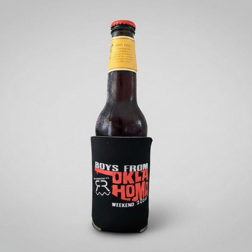 Bottle of beer with a black can cooler labeled 'Boys from Oklahoma' on a light gray background