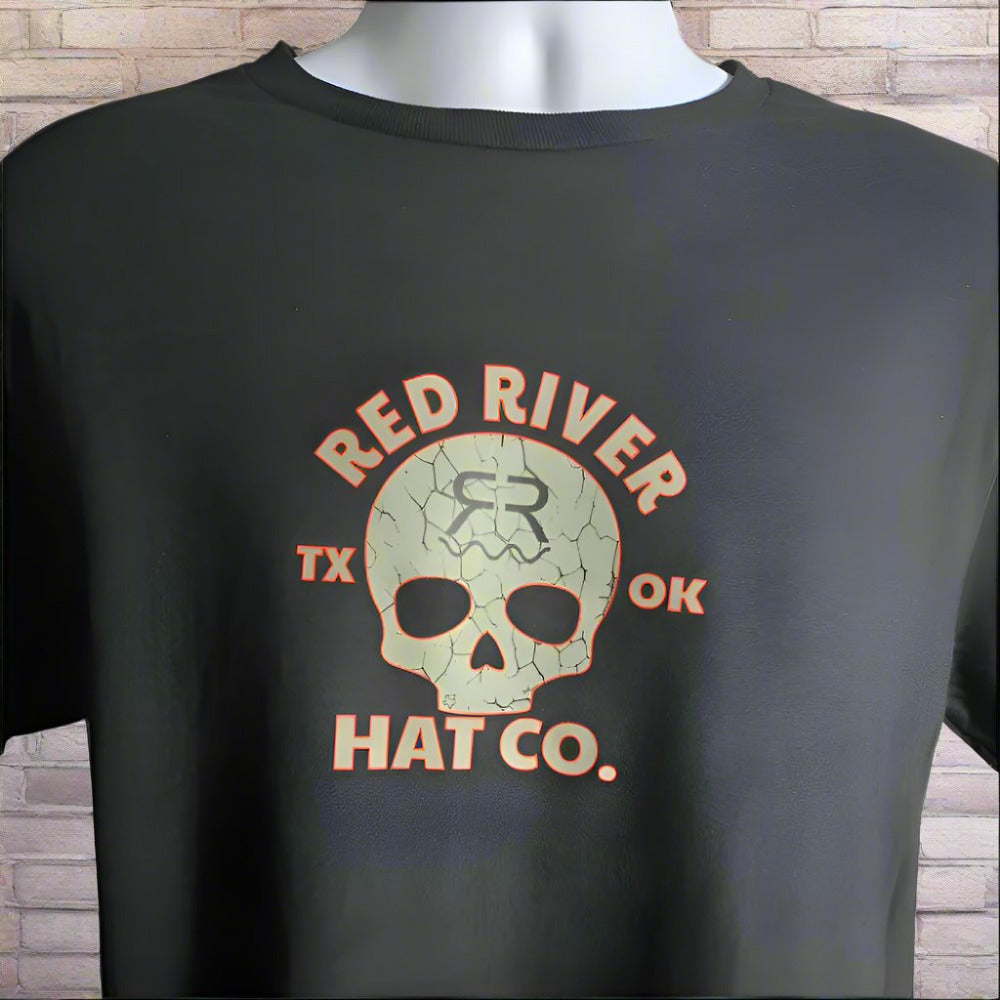 A black short sleeve t-shirt with a 'Cracked Skull' design and the text 'RED RIVER HAT CO. TX OK' printed on the front.