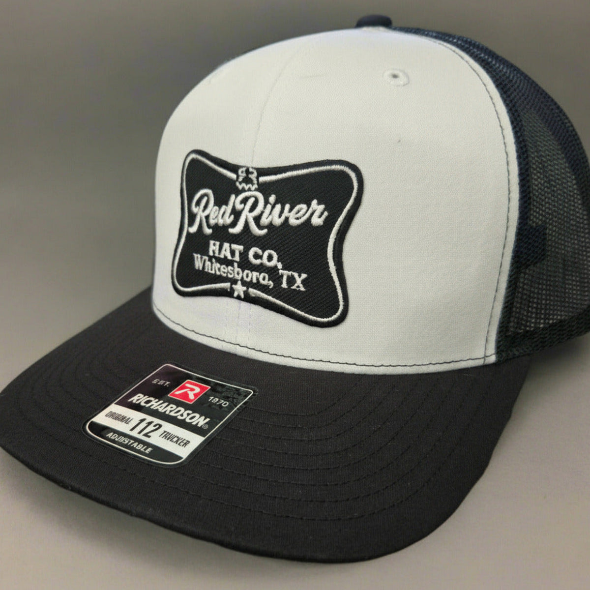 White and black cap with 'Red River Hat Co' logo on a gray background