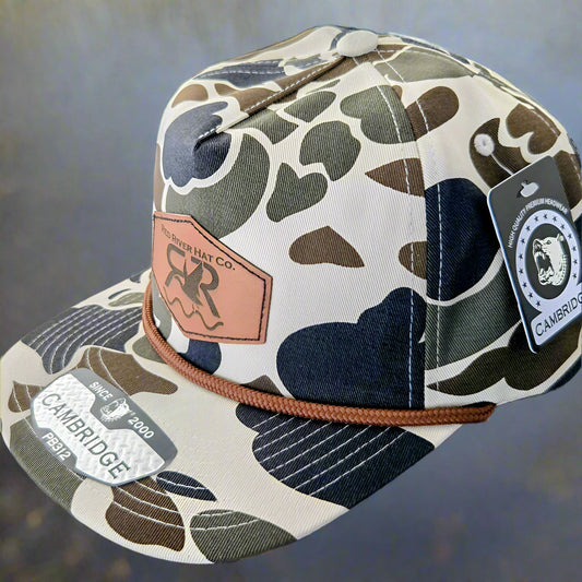 Camouflage-patterned cap with brand tag on a gray surface