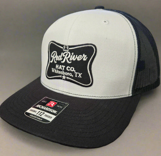 White and black cap with 'Red River Hat Co' logo on a gray background