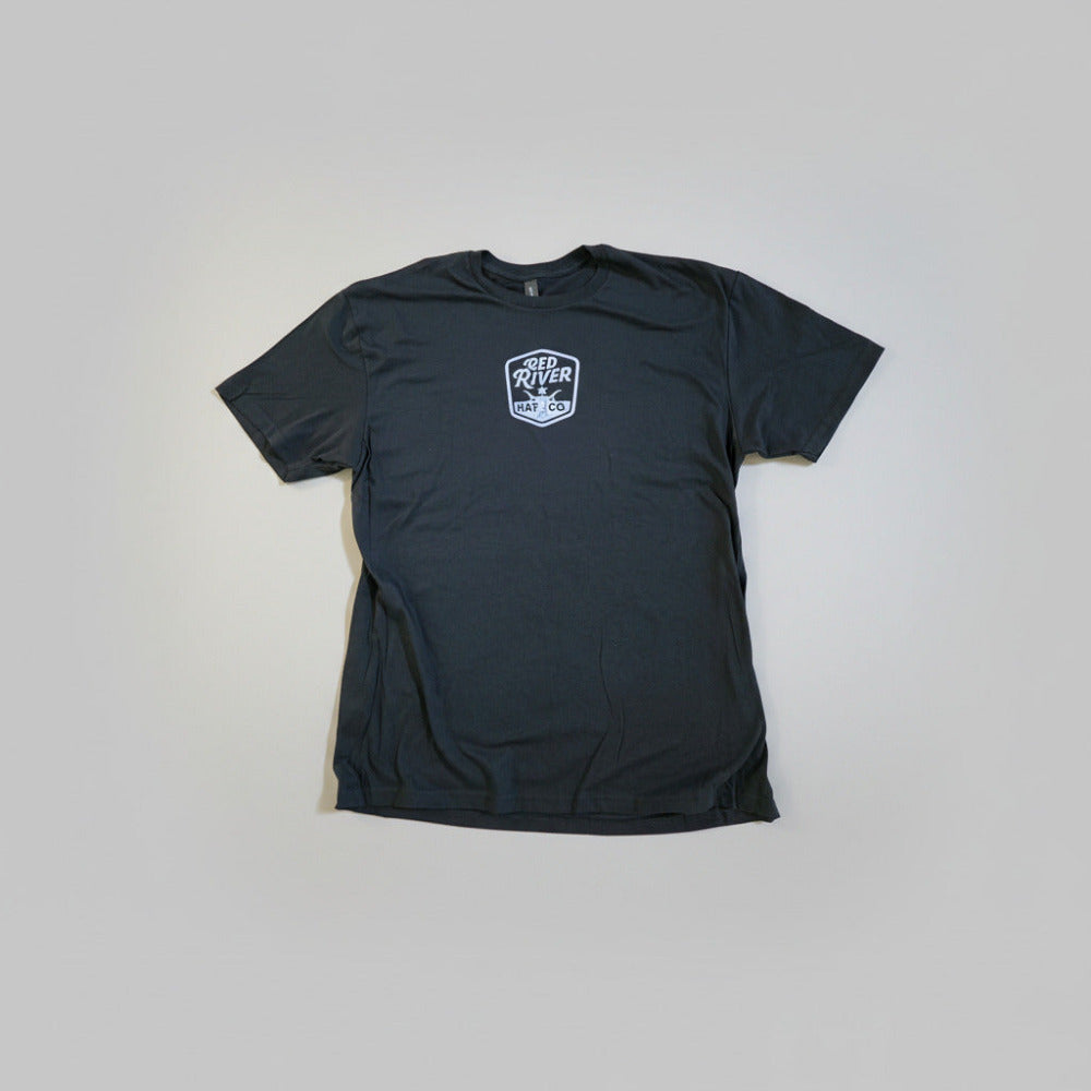 Black t-shirt with 'Red River Hat Co' logo on a wooden surface