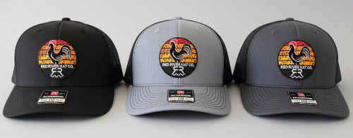 Three baseball caps with a rooster logo on a gray background