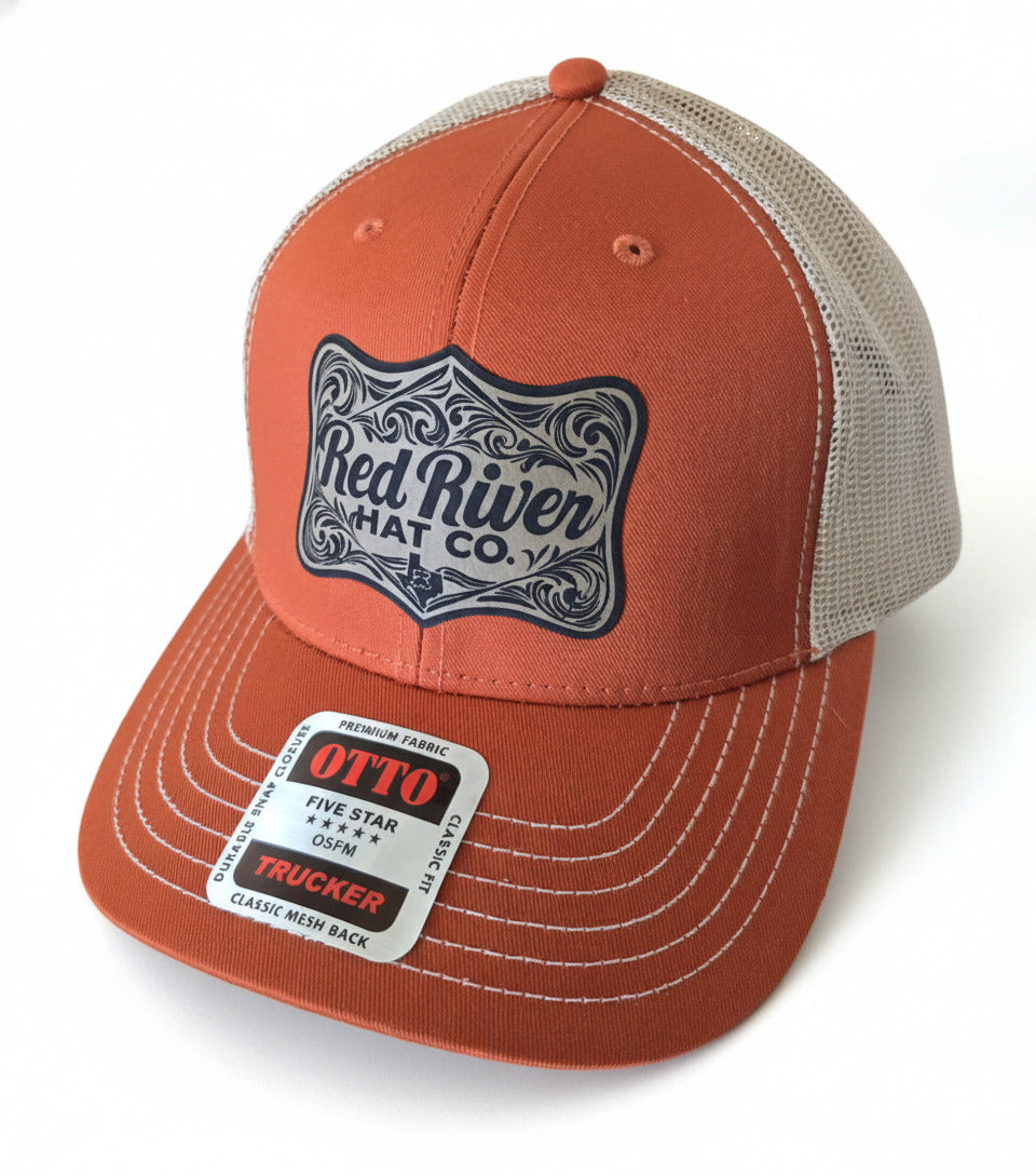 Orange trucker hat with 'Red River Hat Co.' logo on a countertop